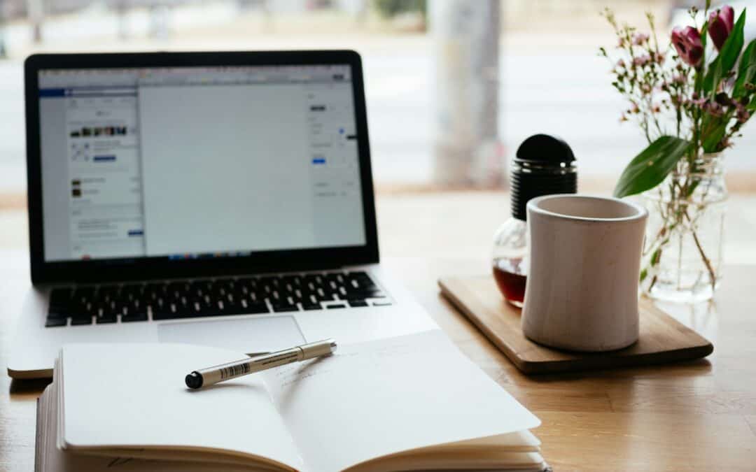 Laptop, open notebook, and coffee on a desk, representing writing and blogging setup for comparing Substack and WordPress